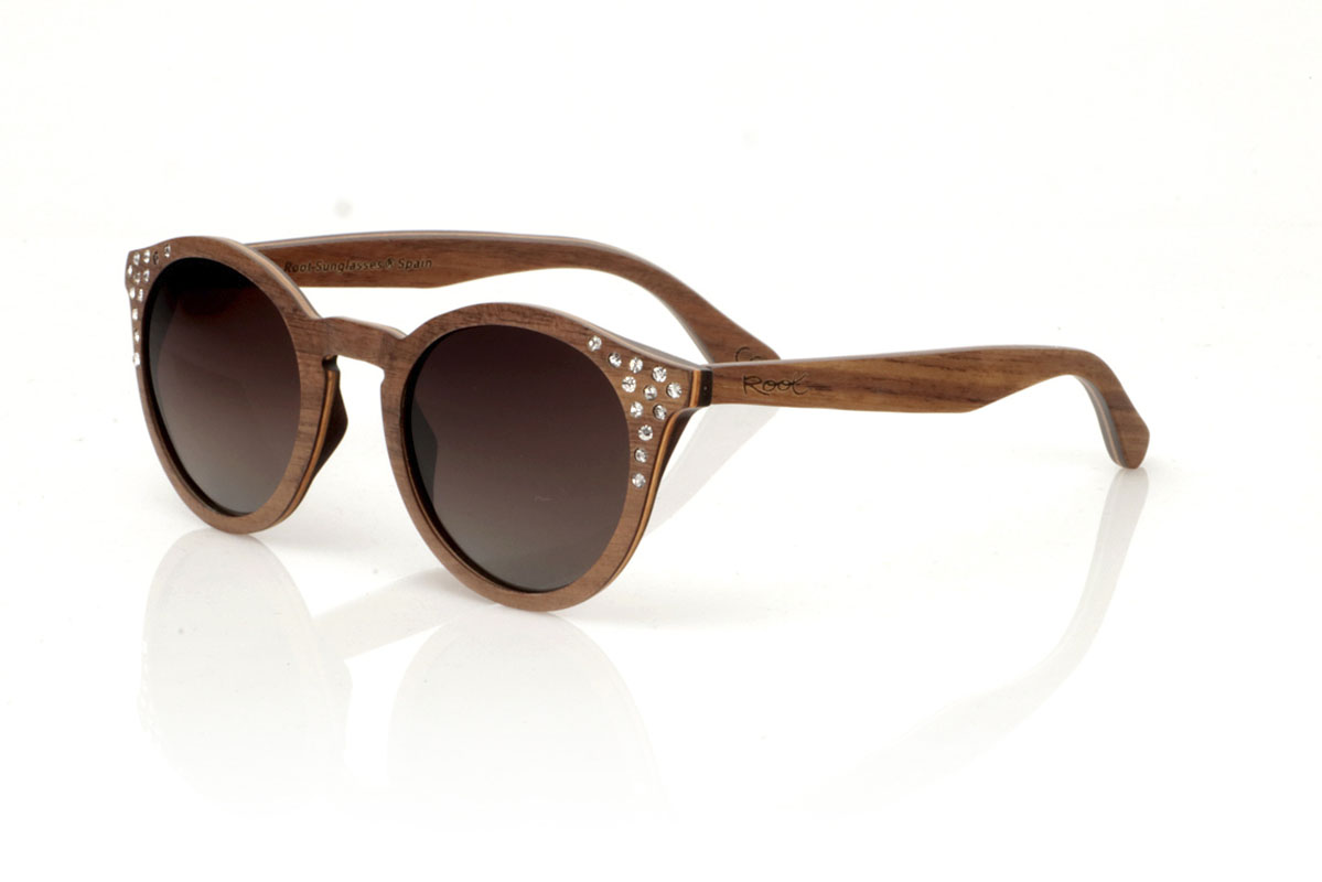 Wood eyewear of Walnut LANA. LANA wooden sunglasses, from our collection of organic glasses, entirely made of laminated walnut wood. This model perfectly combines natural elegance with an iconic design: a rounded shape with a straight eyebrow, creating a visual balance that enhances any type of face. But what really sets LANA apart are the sparkling Czech crystals embedded at the ends of the brows, adding a touch of light and sophistication. Ideal for those looking to stand out with a unique accessory, LANA is not just a pair of glasses, but a statement of style and ecological awareness. Measurements 147x50mm Caliber 47 for Wholesale & Retail | Root Sunglasses® 